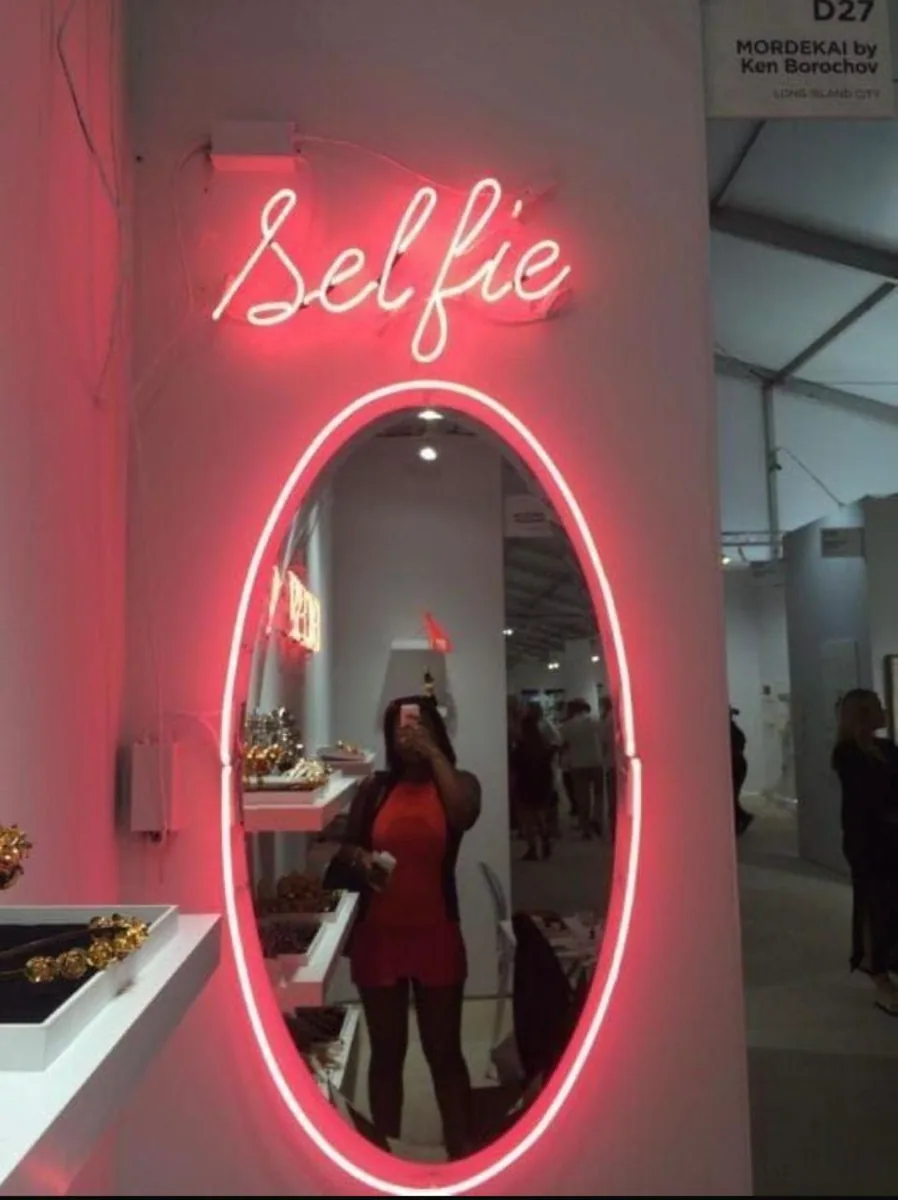 Espejo con letrero de neón que dice Selfie